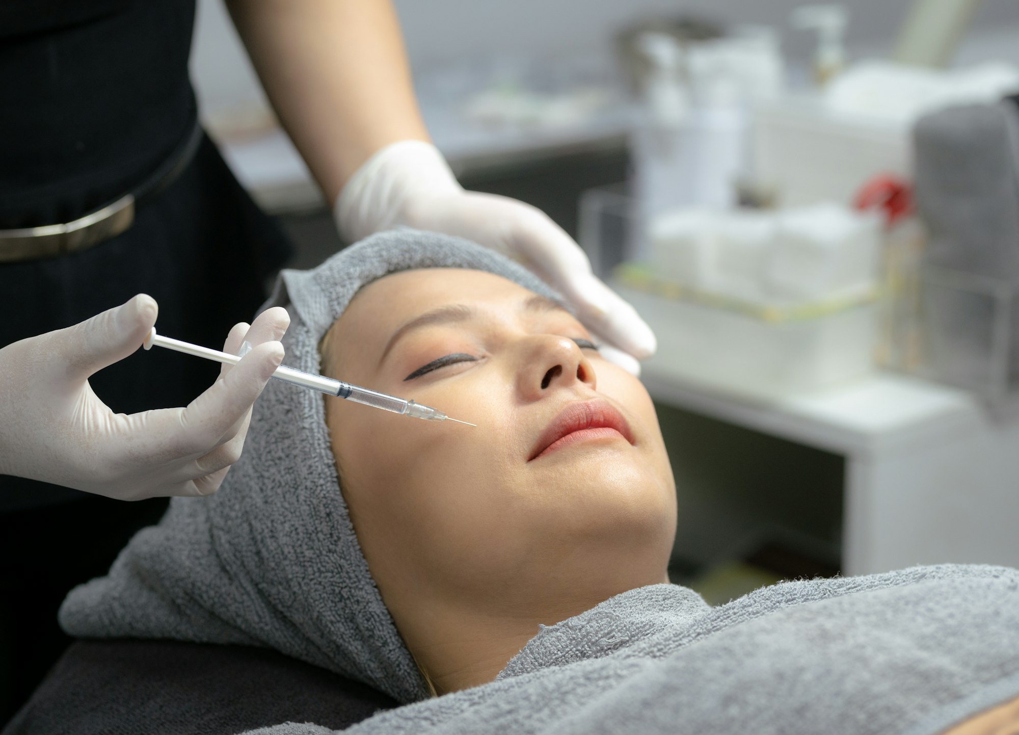 A young woman injects vitamins into her face in a beauty clinic.